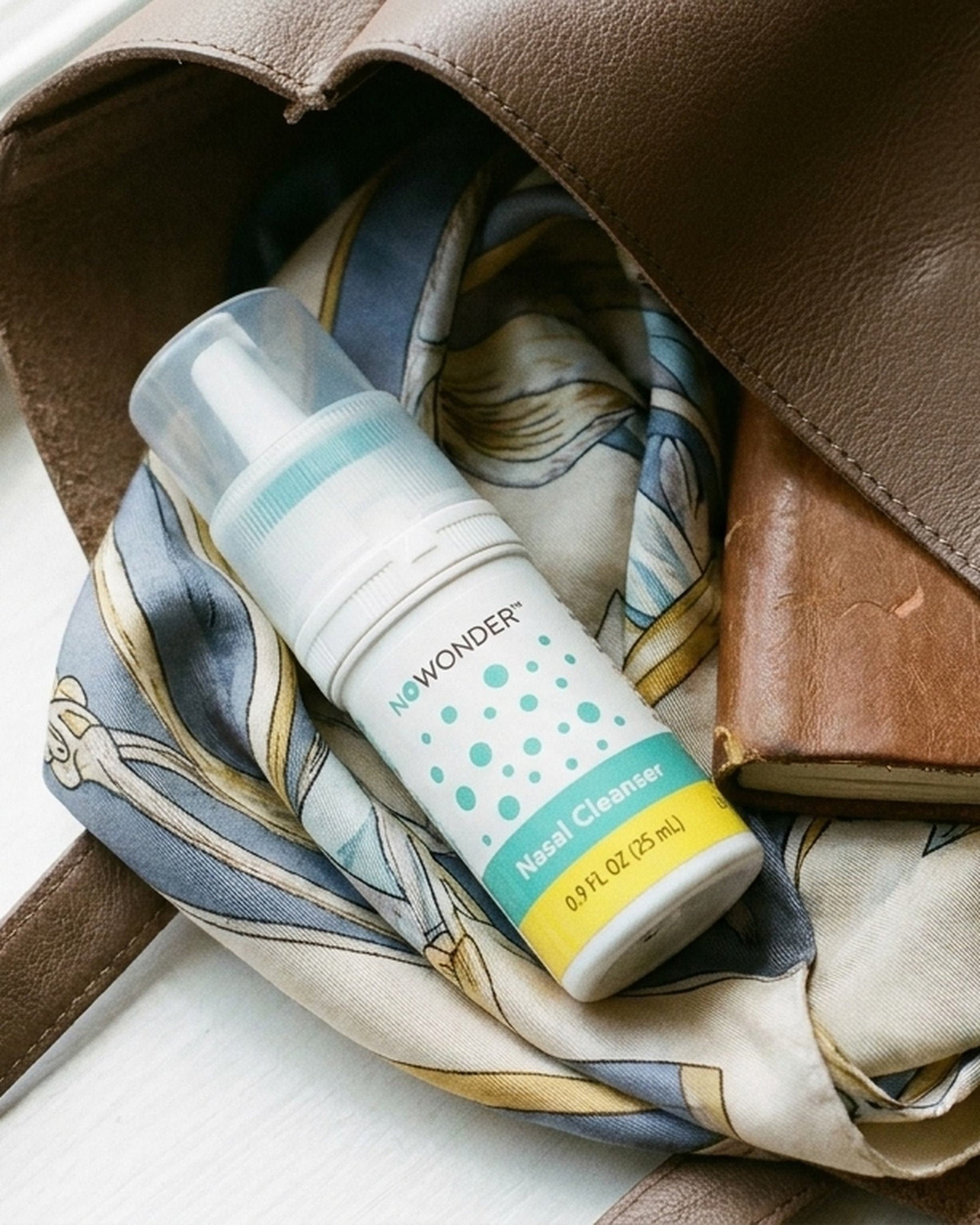 A bottle of NOWONDER Nasal Cleanser  inside an open brown leather bag.