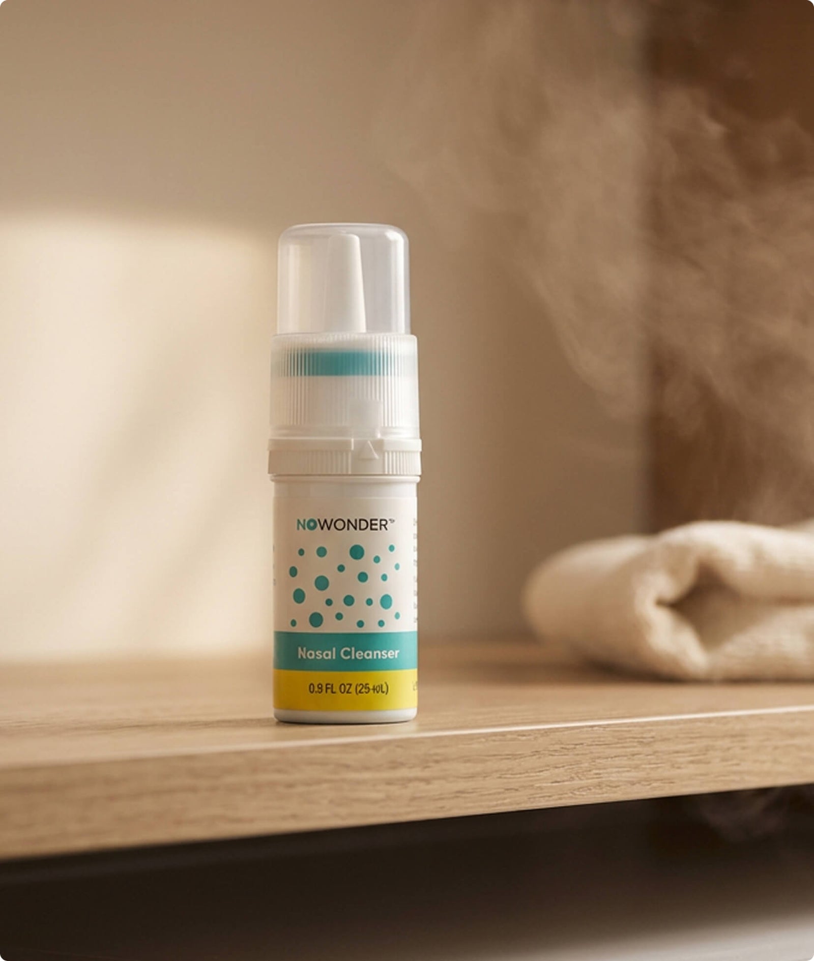 A bottle of NOWONDER Nasal Cleanser sits on a wooden shelf, with a soft-focus beige towel in the background.