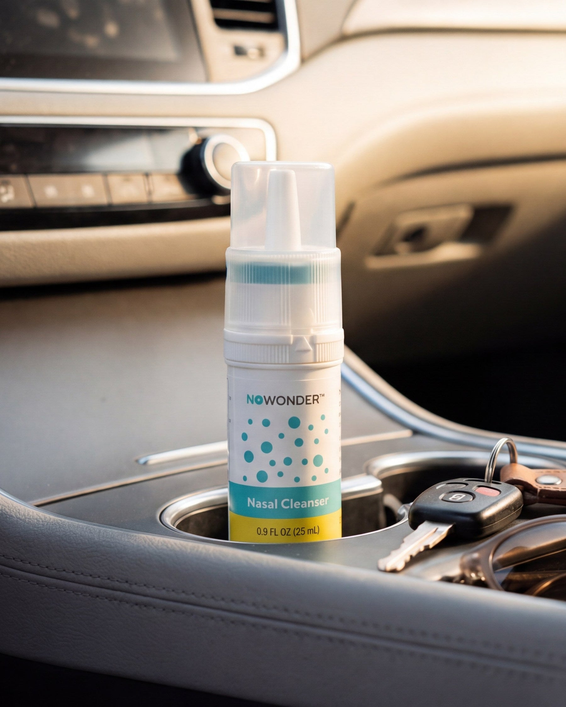 A bottle of NOWONDER Nasal Cleanser sits in a car cup holder