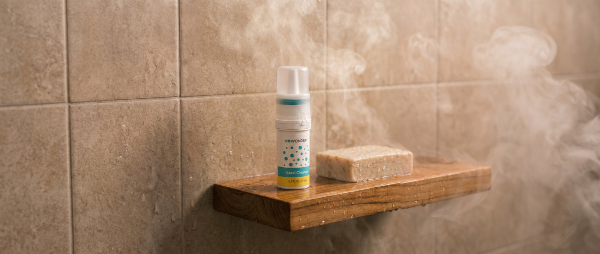 NOWONDER Nasal Cleanser on a teak shower shelf, wide steam scene