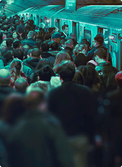 A crowded subway station platform with a train arriving in the background, captured in a strong teal-blue tint. Passengers are seen from behind.